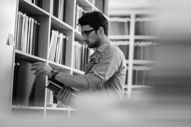 Young man taking books in a library.